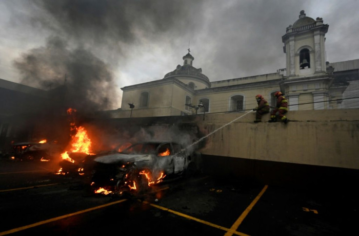 Firemen try to put out a burning car in the parking lot of Guatemala's Congress building, where protesting ex-soldiers  clashed with riot police