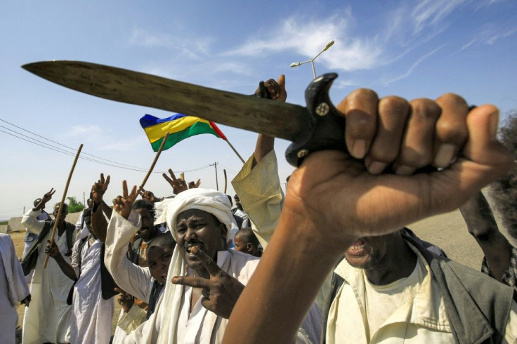 Members of the Beja ethnic group of eastern Sudan wave the flag of the Beja Congress political group as they demonstrate outside the Osman Digna port