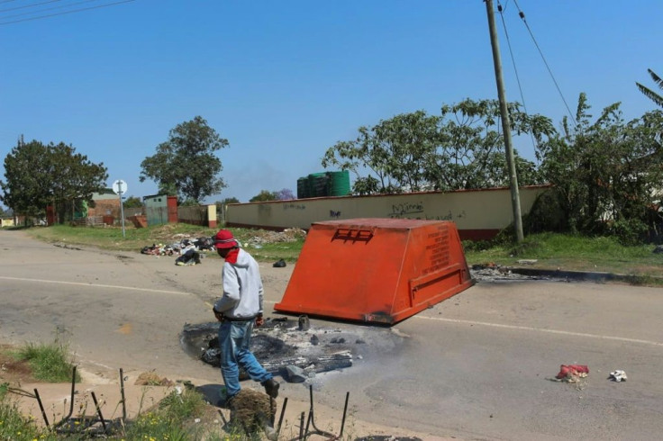 A man passes by a blocked road in the Msunduza towship of Mbabane on October 20, 2021
