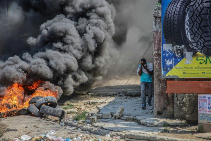 A man walks by burning tires during a general strike in protest at kidnappings and insecurity in Port-au-Prince on October 18, 2021