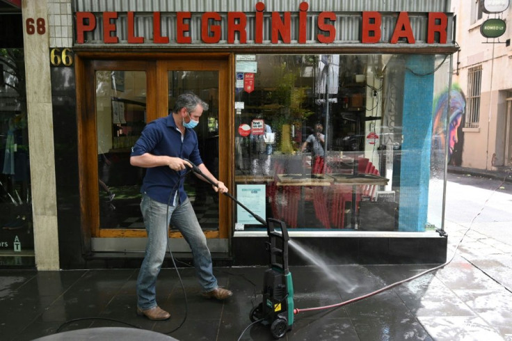David Malaspina, owner of Pellegrini's Espresso Bar, hoses down the front of his establishment ahead of the expected lifting of coronavirus restrictions
