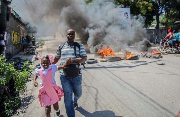 People pass by blazing barricades set by protester angry at fuel prices, as Haiti suffers from deepening social, economic and health crises, as well as a surge of kidnappings by criminal gangs