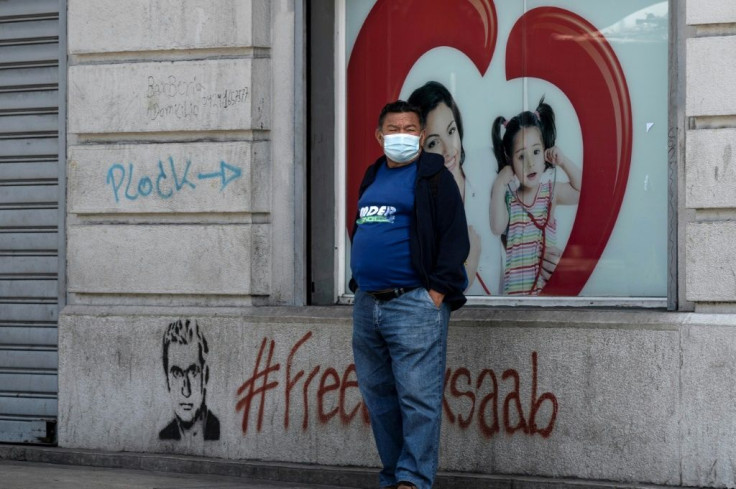 A man stands next to graffiti reading "#FreeAlexSaab" in Caracas on September 10, 2021