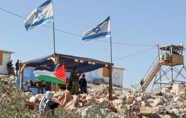 A Palestinian man waves his flag next to the Israeli outpost of Evitar in the occupied West Bank on October 10