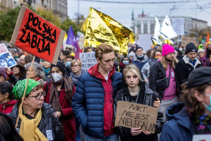 People hold signs with slogans such as "No one is illegal" (pictured) as  they take part in a protest in solidarity with migrants who have been pushed back at Poland's border with Belarus in Warsaw, October 17, 2021