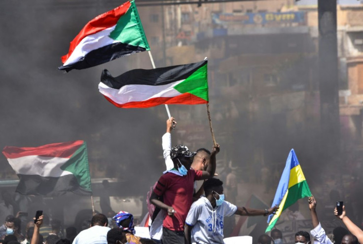 In this file picture taken on October 21, 2021, Sudanese demonstrators raise national flags as they take part in a protest in the city of Khartoum Bahri to demand the government's transition to civilian rule