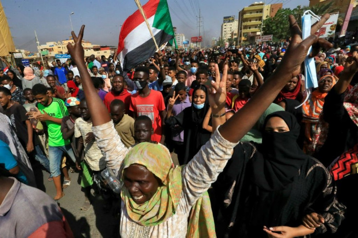 Sudanese protesters lift national flags as they rally on 60th Street in the capital Khartoum