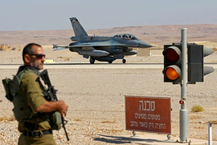 An Israeli soldier stands guard as an F-16 fighter lands during the "Blue Flag" multinational air defence exercise