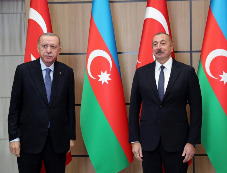 This handout photograph taken and released on October 26, 2021, by the Turkish Presidential Press Service shows Turkey's President Recep Tayyip Erdogan (R) as he is welcomed by Azerbaijan's President Ilham Aliyev (L) in Zangilan