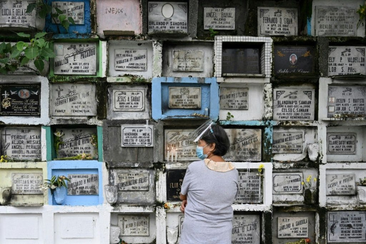 A woman prays in front of the grave of a relative at a cemetery in Manila ahead of All Saints' Day