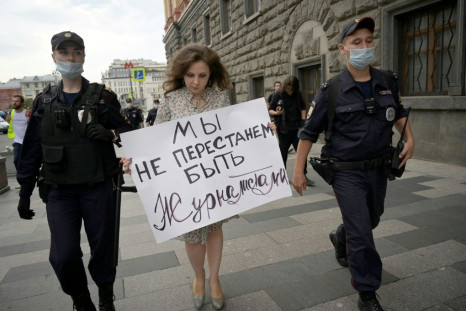 Police detain a journalist who holds a placard that reads "We don't stop being journalists" in solidarity with collegues added to the list of "foreign agent" media near the headquarters of Russia's Federal Security Service in August 2021