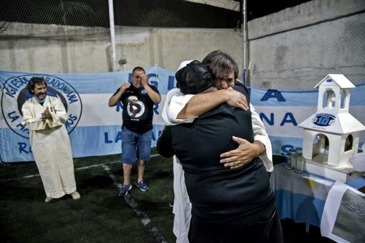 Members of the 'Maradonian Church' embrace during a ceremony in Rosario, Argentina to mark what would have been the 61st birthday of the football legend; those dressed in white were 'baptized' into the 'church'