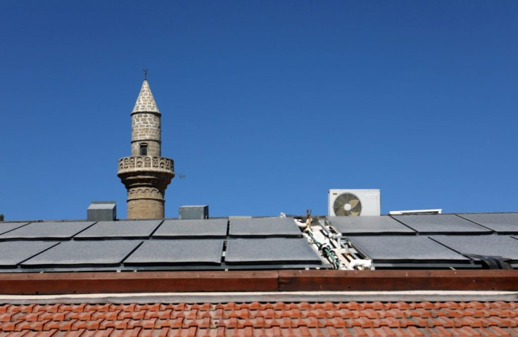 Solar panels cover the roof of a house in the village of Kalavasos, in front of a mosque minaret, but Cyprus is still struggling to increase its use of renewable power