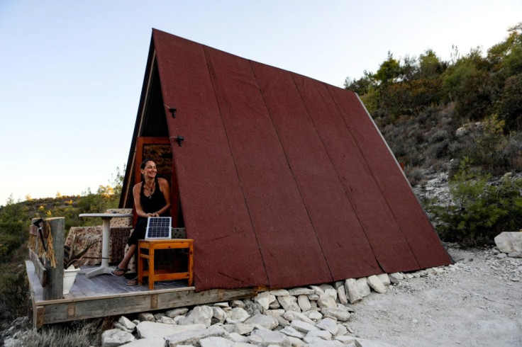 Melissa Ahearn sits at the entrance of the A-frame dwelling which she lives in and built with her partner to run exclusively on solar energy