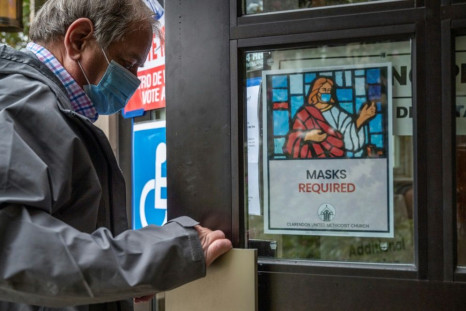A man arriving to vote,  passes a sign with an image of Jesus wearing a mask advising anyone entering a church to wear a mask as a precaution against Covid-19 in Arlington, Virginia on November 2, 2021