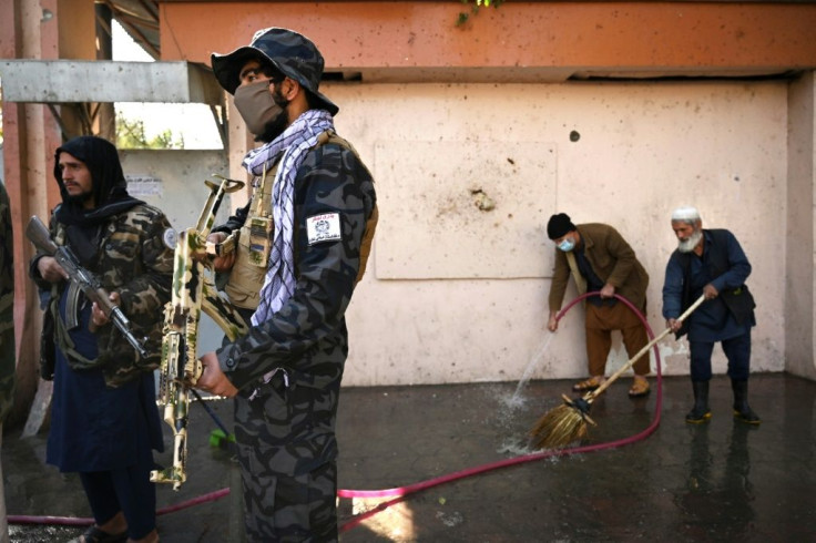 Cleaners rinse blood from the pavement a day after the attack