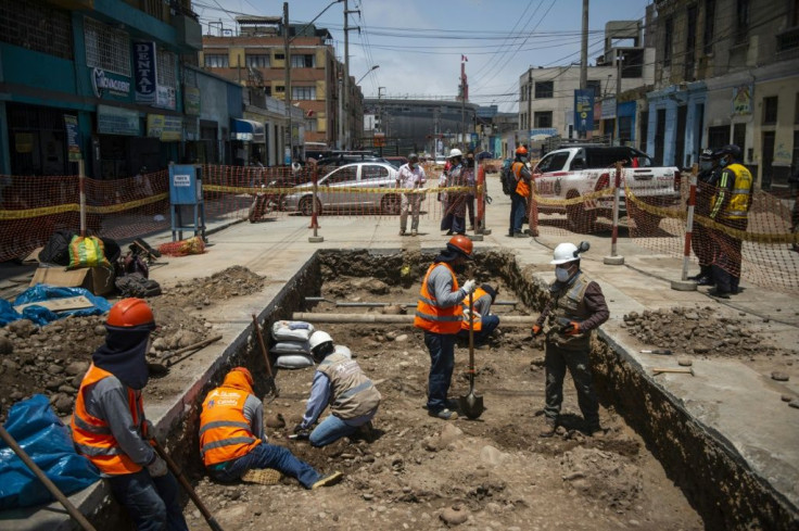 Specialists work around the ancient burial site found by a crew laying a natural gas pipe under a street in Lima, Peru on November 04, 2021