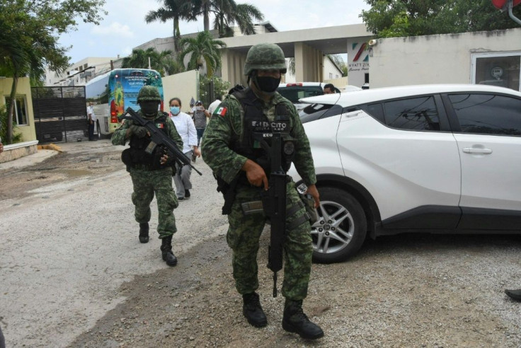 Mexican soldiers walk outside the Hyatt Ziva Riviera hotel in Puerto Morelos after a gang shooting left two suspected drug dealers dead