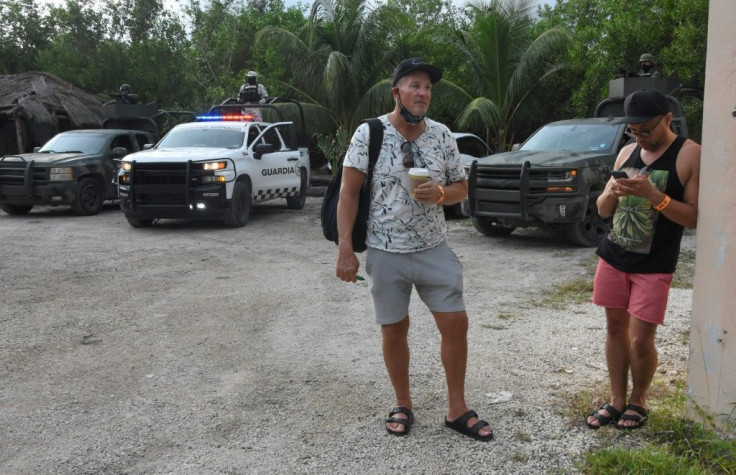 Tourists and Mexican police wait outside the Hyatt Ziva Riviera hotel in Puerto Morelos after a gang shooting nearby sparked panic among guests