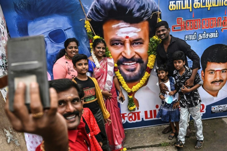 Fans take selfies with a billboard showing Bollywood star Rajinikanth ahead of the release of his film 'Annaatthe'