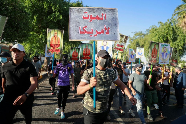 Supporters of Iraq's Hashed al-Shaabi paramilitary network carry anti-US and anti-Israel placards during a procession towards one of the Green Zone entrances in the capital Baghdad
