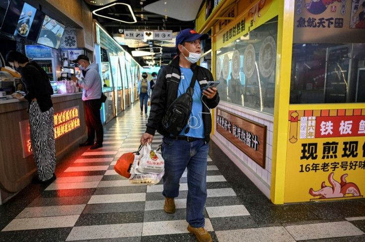 Food delivery driver Zhuang Zhenhua looks for a restaurant to pick up food at a food mall in Beijing