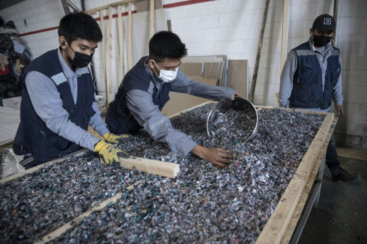 Men work at a factory that recycles used clothes discarded in the Atacama desert for housing insulation panels, in Alto Hospicio, Iquique, Chile