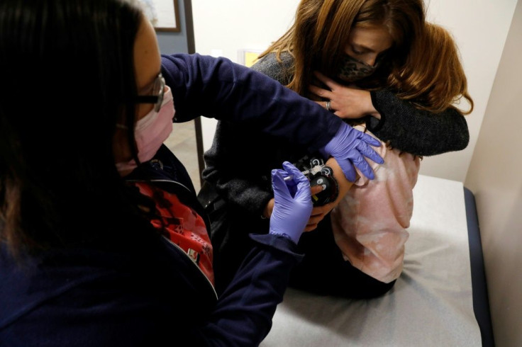 A six-year-old child is comforted by her mother as she receives her first dose of the Pfizer-BioNTech Covid-19 vaccine