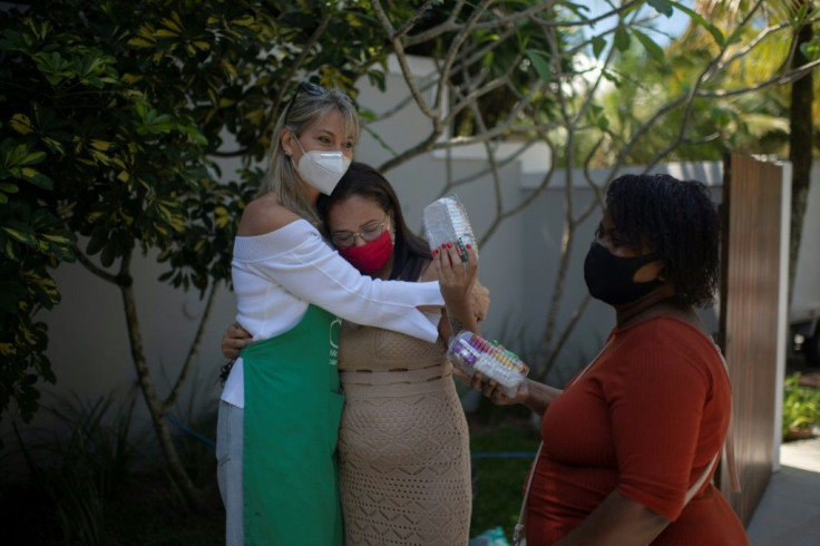 The founder of the NGO One By One Teresa Stengel (L) embraces Vanessa Moraes as she distributes sanitary pads, in Rio de Janeiro, Brazil