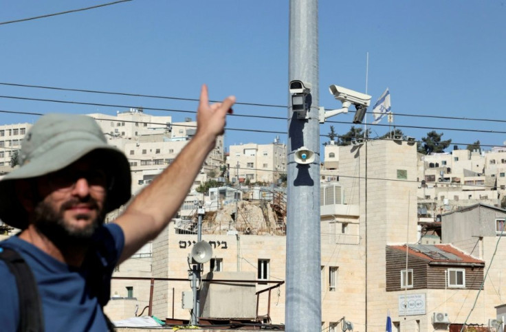 A man points at surveillance cameras in the Palestinian city of Hebron, where an organisation working with former soldiers says facial recognition technology is targeting Palestinians