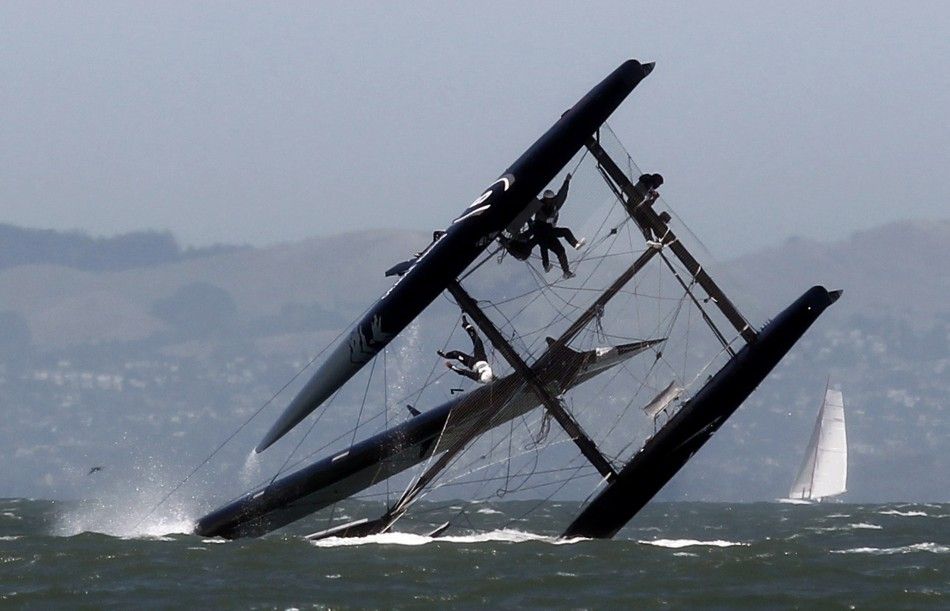 A sailor falls onto the wing of an Oracle Racing AC45 boat after it capsized during an exhibition race in San Francisco Bay