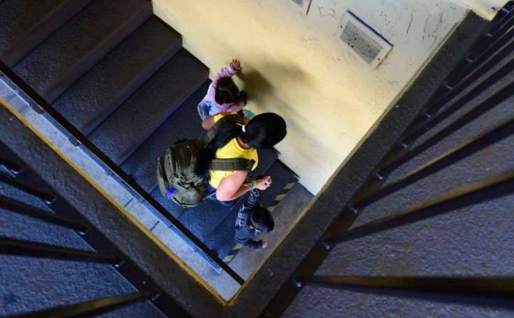 A mother from Venezuela and her two children make their way down a flight of stairs at a migrant shelter in San Diego, California on November 9, 2021