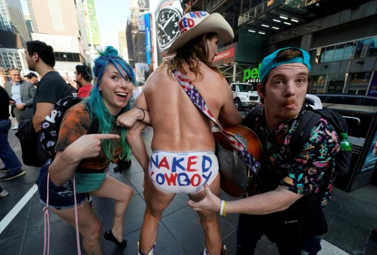 Tourists pose with the Naked Cowboy in Times Square on November 9, 2021 in New York, New York