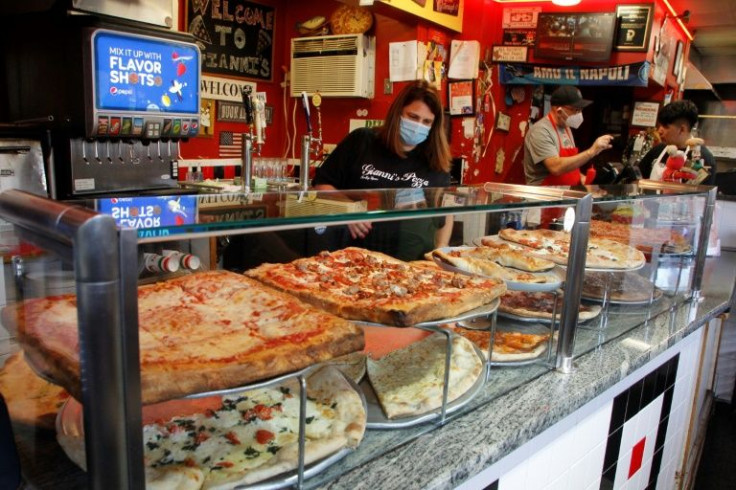 Gianni Esposito (C) speaks to an employee as another serves pizza at Gianni's Pizza in Wilmington, Delaware on November 12, 2021