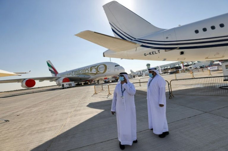 Two men stand next to an Acropolis Aviation Airbus A320-251N aircraft, with an Emirates Airbus A380 aircraft in the background, at the 2021 Dubai Airshow in the Gulf emirate on November 14, 2021