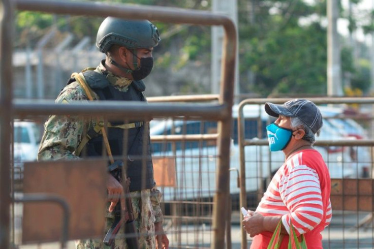 A woman speaks with a soldier outside a prison in Ecuador where rioting left at least 68 inmates dead