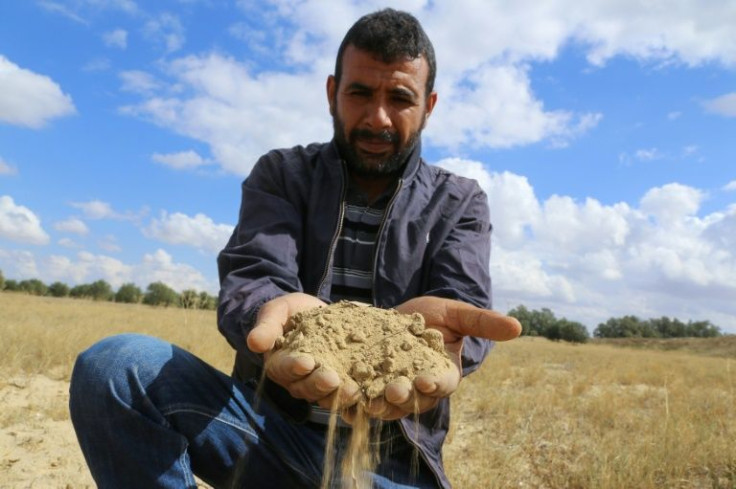 A farmer holds a handful of soil parched because of drought in Tunisia's east-central area of Kairouan, on October 20, 2021