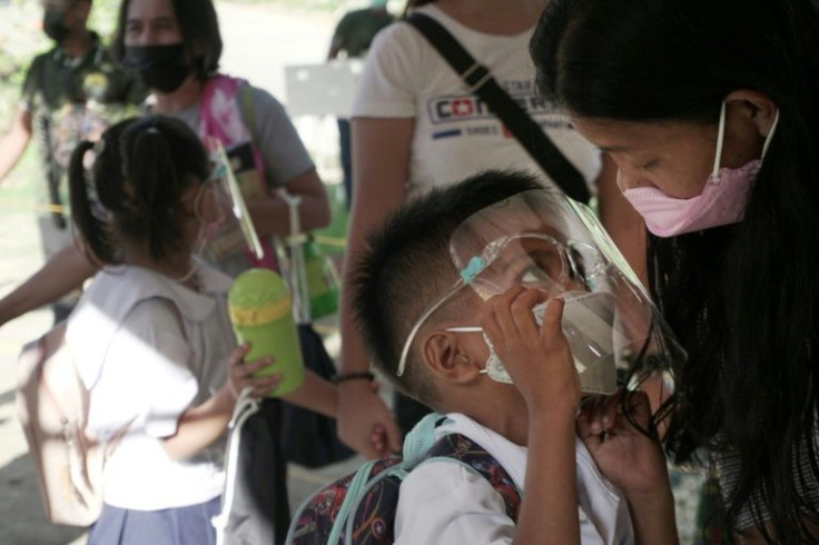 A mother talks to her son wearing a face mask and shield prior to attending classes