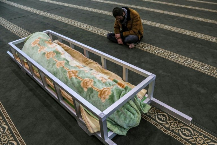 A man sits in a mosque by the repatriated body of Iraqi Kurdish migrant Gailan Diler, who died while trying to illegally cross into Poland via Belarus, during his funeral in Arbil, the capital of Iraq's northern autonomous Kurdish region