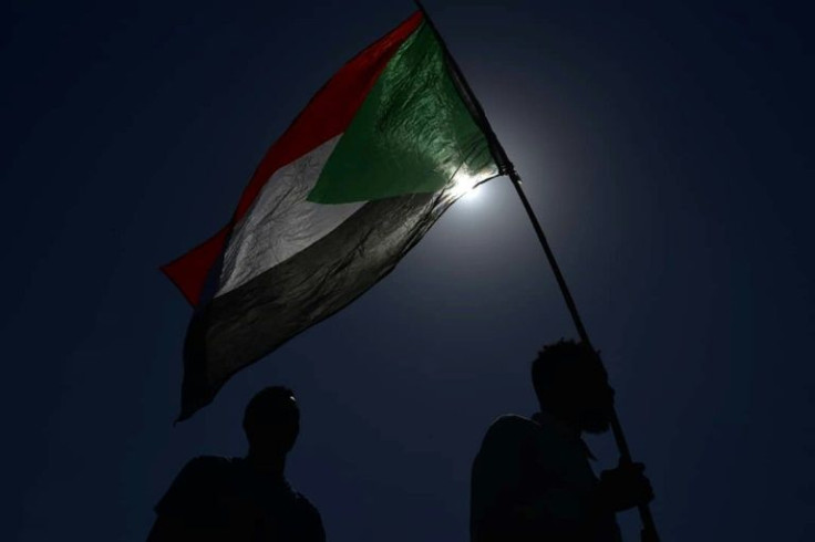 A man stands waving a Sudanese national flag as people protest against an army power grab on November 13, 2021