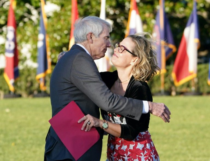 Republican Senator Rob Portman and Democratic Senator Kyrsten Sinema meet at the infrastructure signing ceremony at the White House