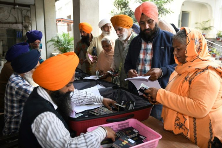 Sikh pilgrims collect their passports on the eve of travelling to Pakistan to celebrate the birth anniversary of Guru Nanak