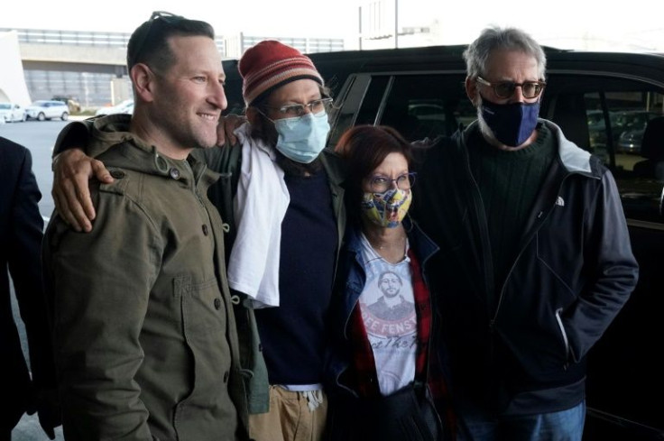 Danny Fenster, wearing a hat, is reunited with his family at JFK airport in New York on November 16, 2021 after being released from prison in Myanmar