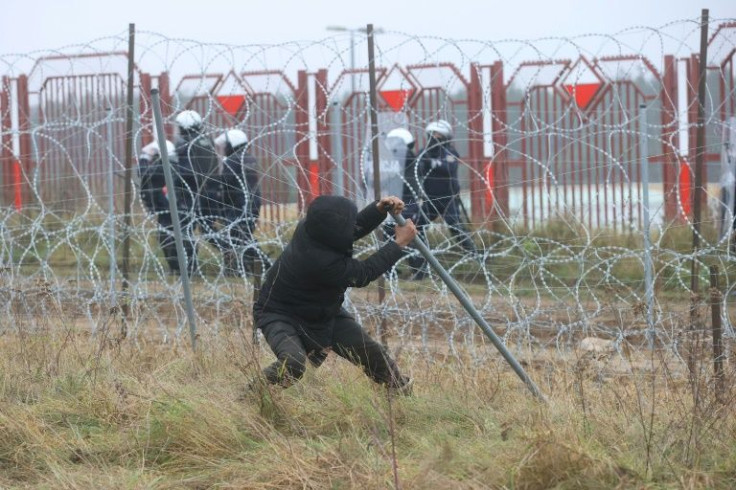 A man attempts to pull down a border fence as migrants attempt to cross into Poland from Belarus on Tuesday
