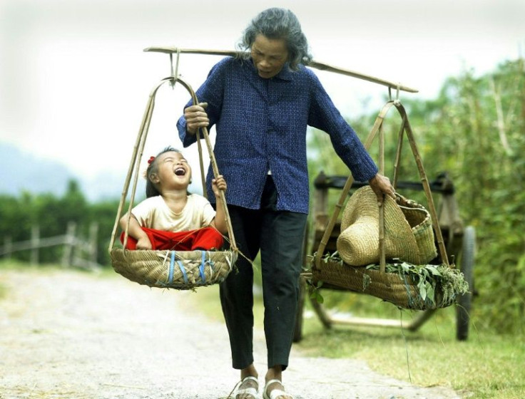 A grandmother carries her laughing granddaugher outside the tourist hotspot of Yangshou in southern China