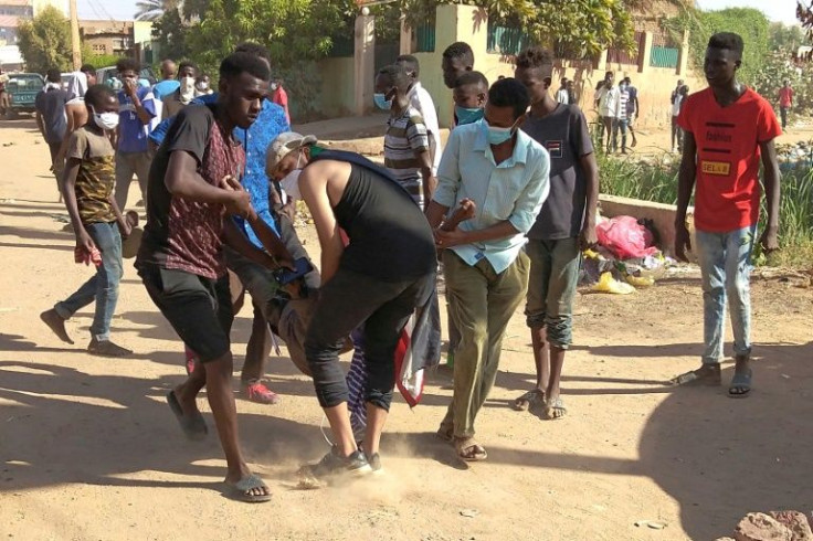 Sudanese anti-coup protesters come to the assistance of a wounded comrade during clashes with security forces on Wednesday in Khartoum's twin city of Omdurman