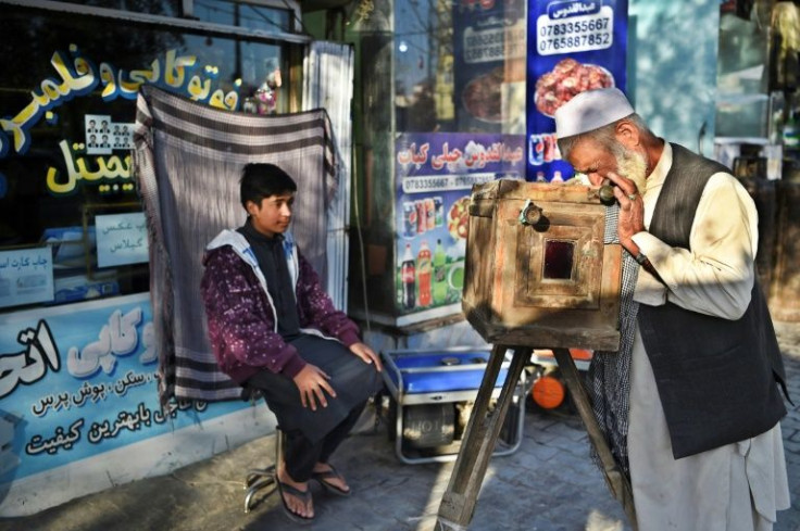Haji Mirzaman takes a portrait of a boy with his homemade wooden box camera known as a 'kamra-e-faoree'