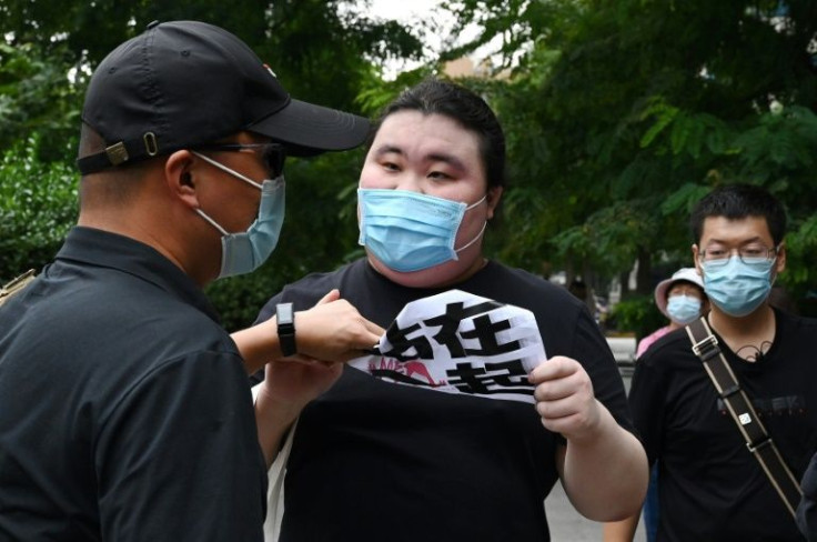 A plain-clothes policeman takes away a sign which reads "We Stand Together" from a supporter of Zhou Xiaoxuan outside court