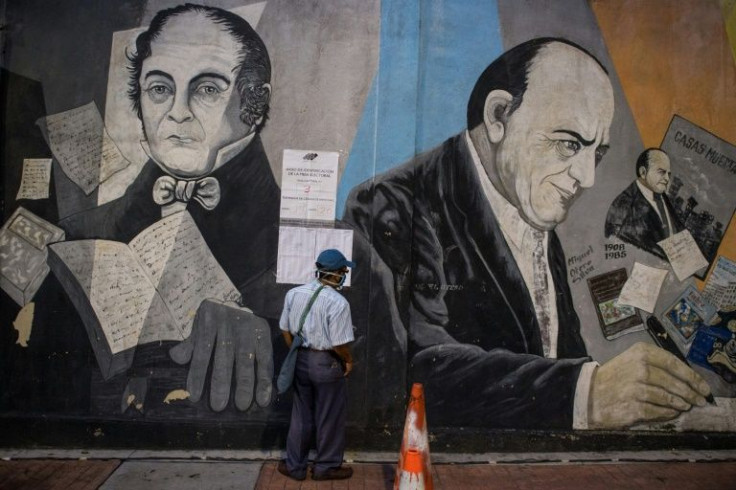 A man looks for his name in the register at a polling station in Caracas, next to a mural depicting late Venezuelan President Hugo Chavez, during regional and municipal elections in Venezuela on November 21, 2021