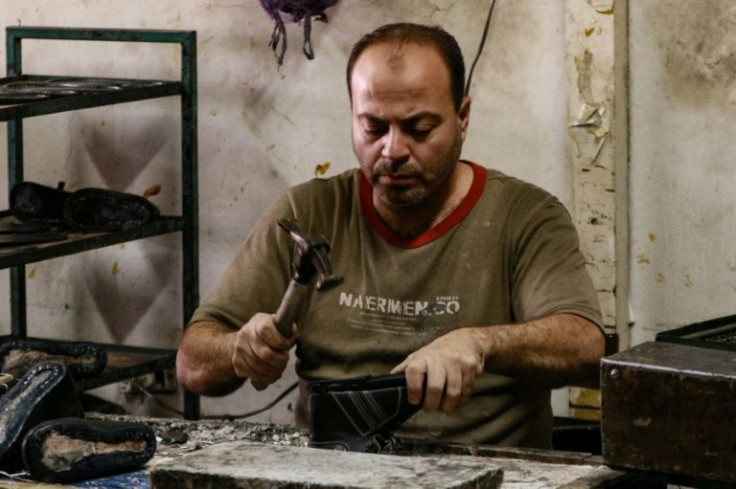 One of the five out of 42 remaining employees working for Jamil Kopti nails parts of a shoe at the workshop in Jordan's capital